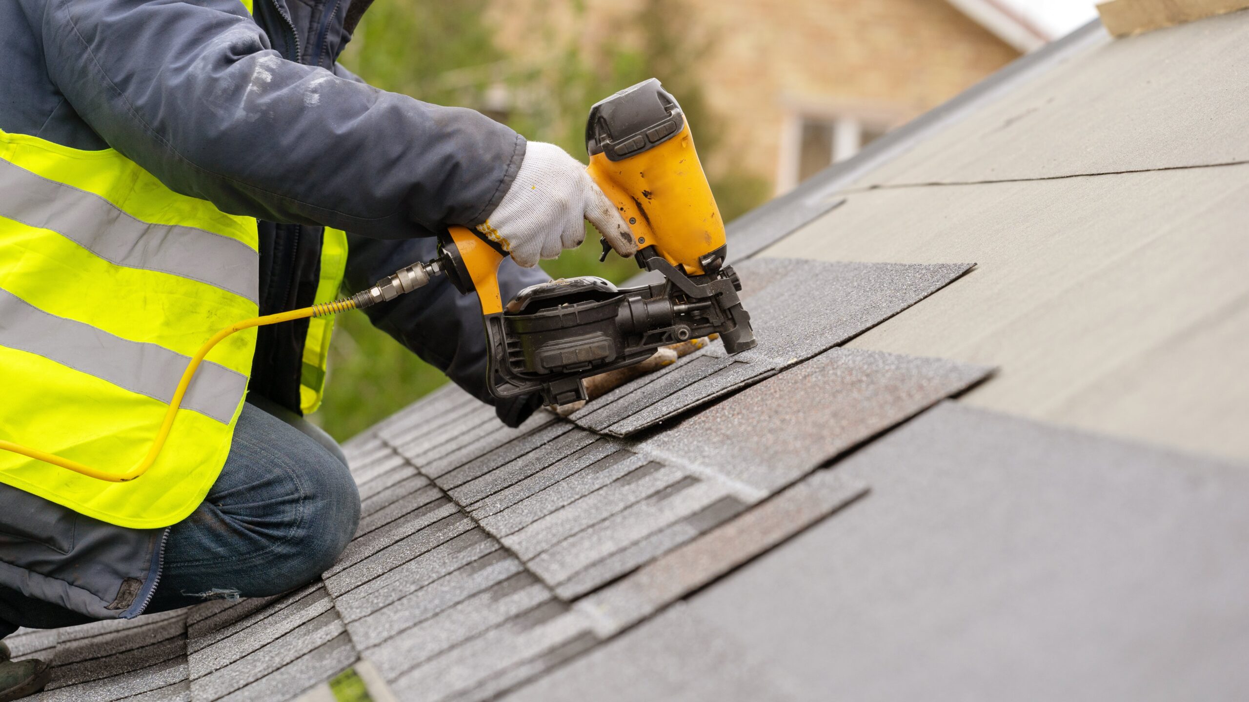 roofer nailing residential shingles into decking 